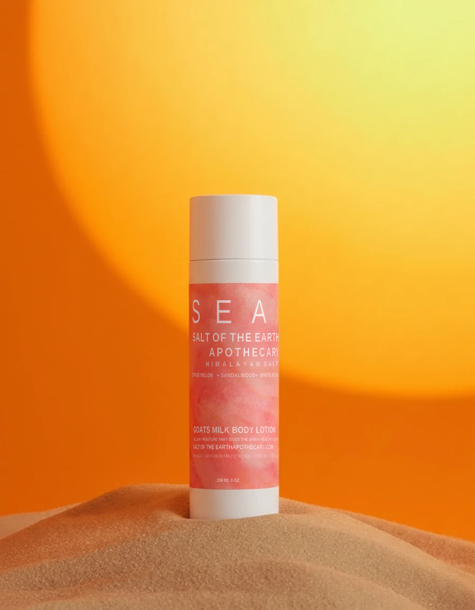 Pink lotion bottle with white cap on a sand-like surface against an orange gradient background