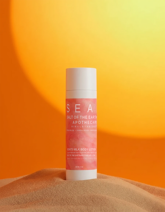 Pink lotion bottle with white cap on a sand-like surface against an orange gradient background